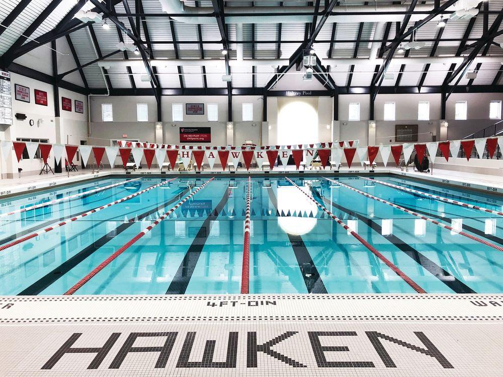 Indoor swimming pool with lanes and red and white flags, under a high arched ceiling.